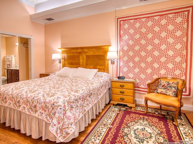 bedroom featuring crown molding, hardwood / wood-style flooring, and ensuite bathroom