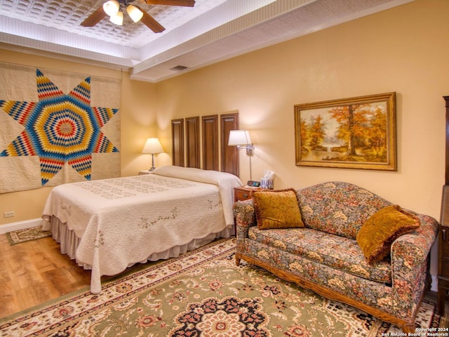 bedroom featuring hardwood / wood-style flooring, ornamental molding, and ceiling fan