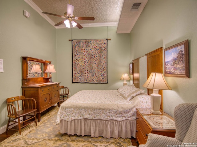 bedroom featuring ceiling fan, ornamental molding, wood-type flooring, and a textured ceiling