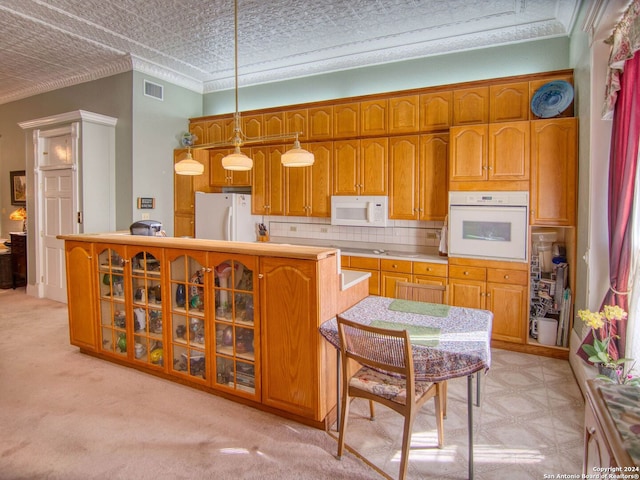 kitchen featuring crown molding, light colored carpet, pendant lighting, white appliances, and backsplash