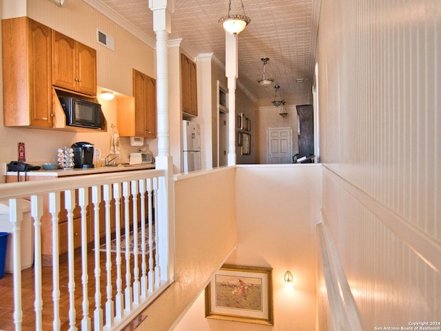 interior space with crown molding, black microwave, and white fridge