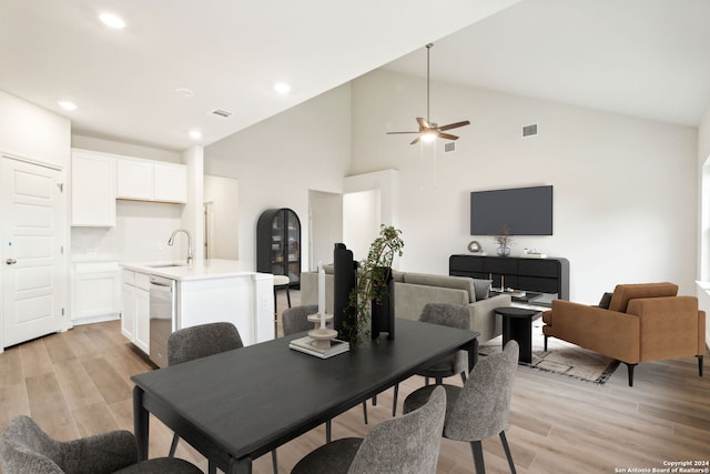 dining space with ceiling fan, light hardwood / wood-style floors, sink, and high vaulted ceiling