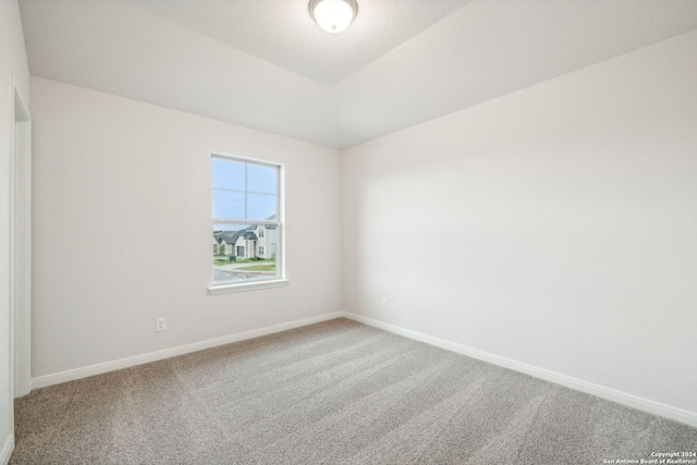 carpeted spare room featuring lofted ceiling