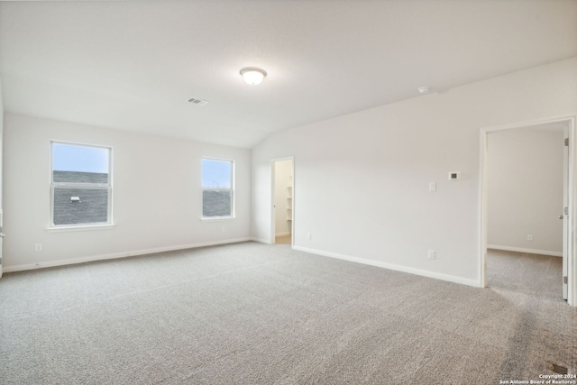 unfurnished room featuring light colored carpet, a healthy amount of sunlight, and vaulted ceiling