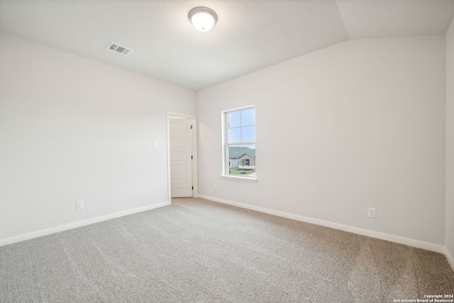 carpeted empty room featuring lofted ceiling