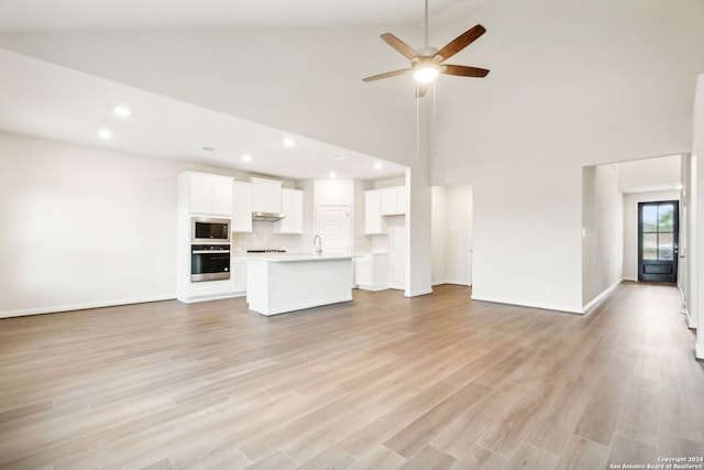 unfurnished living room featuring light hardwood / wood-style floors, high vaulted ceiling, ceiling fan, and sink