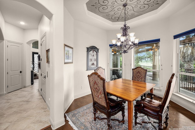 dining room with an inviting chandelier, a tray ceiling, and light tile flooring