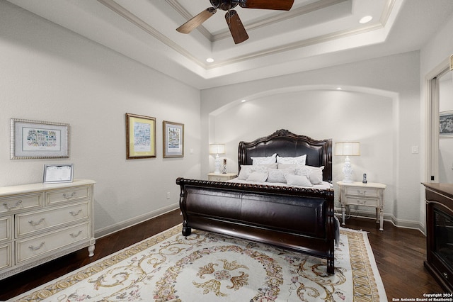 bedroom featuring ceiling fan, a raised ceiling, dark wood-type flooring, and ornamental molding