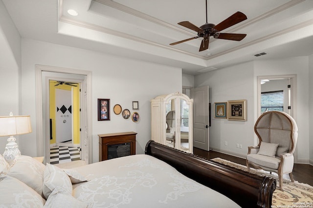 bedroom with wood-type flooring, a raised ceiling, and ceiling fan