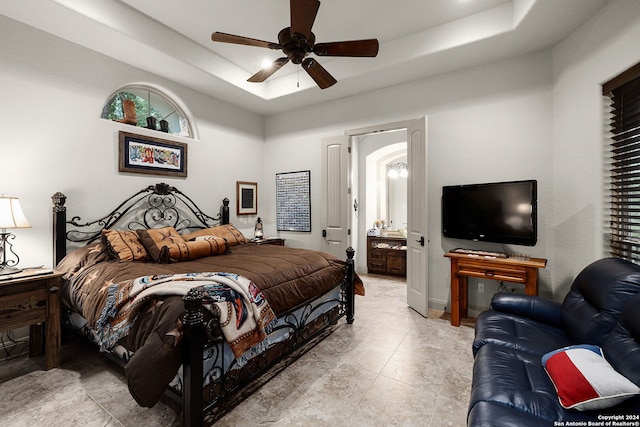 tiled bedroom with a tray ceiling, ceiling fan, and ensuite bathroom