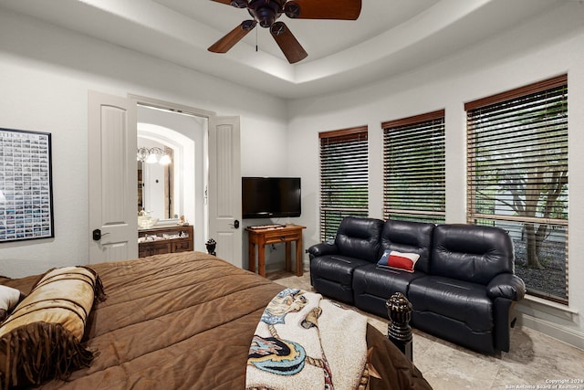 tiled living room with ceiling fan and a raised ceiling