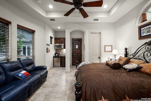 bedroom with ceiling fan, light tile floors, and a tray ceiling