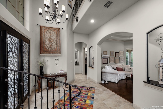 tiled entrance foyer featuring french doors, a chandelier, and a high ceiling