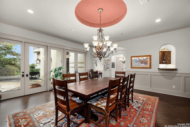 dining room featuring french doors, dark hardwood / wood-style flooring, a tray ceiling, ornamental molding, and a chandelier