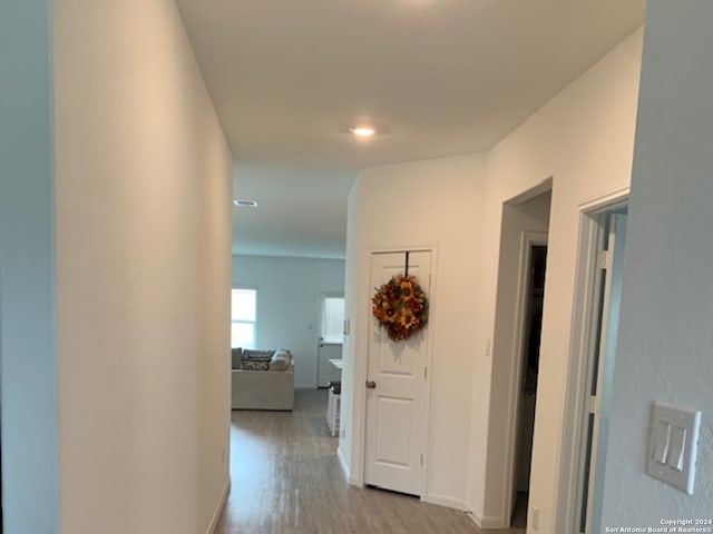 corridor featuring light wood-style flooring and baseboards