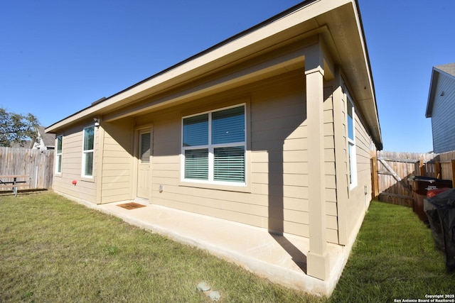 view of side of home featuring fence and a lawn