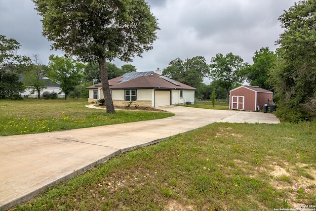 view of front of house with a front lawn, a storage shed, a garage, and solar panels