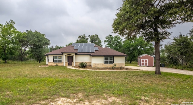 view of front of home featuring solar panels, a storage shed, and a front yard