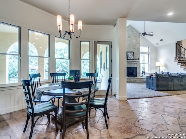 tiled dining space with ceiling fan with notable chandelier, a fireplace, a wealth of natural light, and high vaulted ceiling