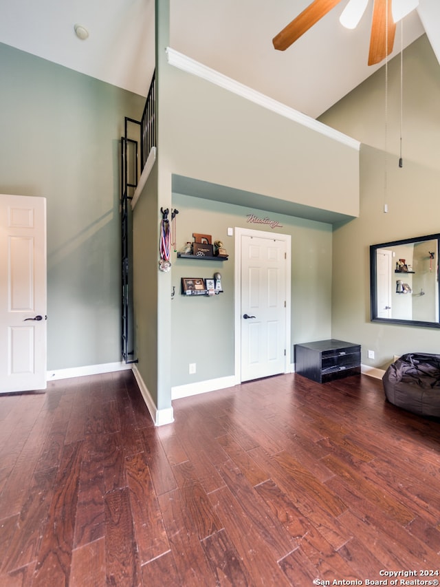 unfurnished living room featuring ceiling fan, dark hardwood / wood-style flooring, and a high ceiling