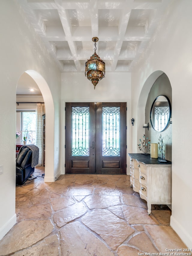 foyer entrance with beam ceiling, coffered ceiling, french doors, and a chandelier