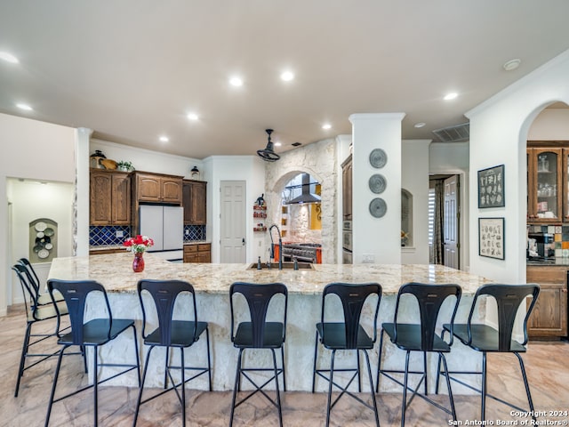 kitchen featuring a kitchen bar, sink, tasteful backsplash, a spacious island, and white refrigerator