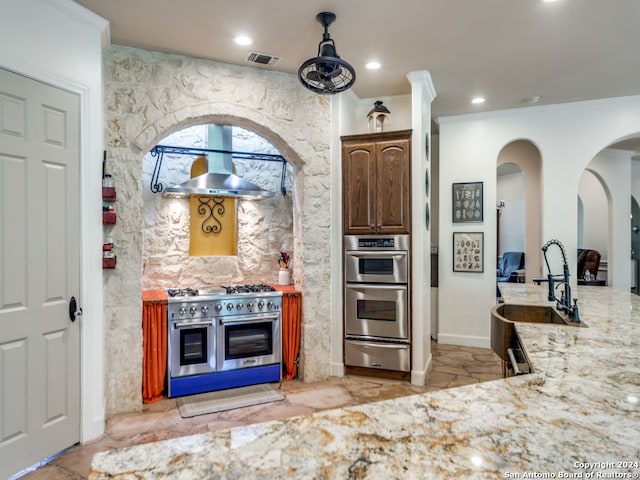 kitchen with light stone counters, stainless steel appliances, sink, light tile floors, and fume extractor