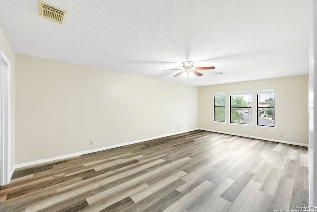 spare room featuring ceiling fan, light wood-type flooring, and a textured ceiling