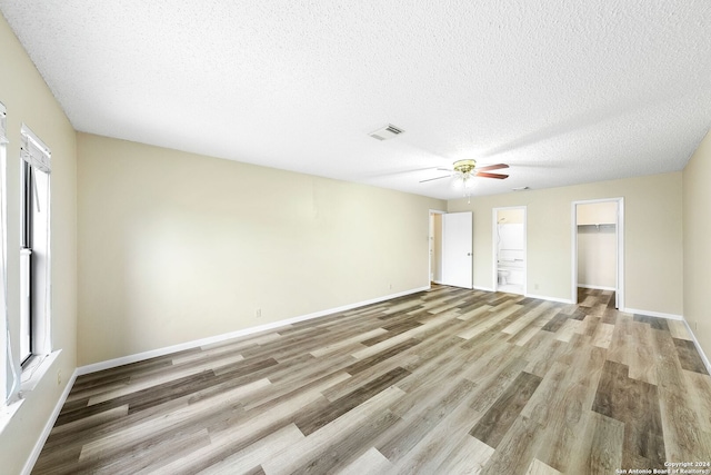 unfurnished room featuring ceiling fan, light wood-type flooring, and a textured ceiling