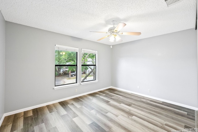 unfurnished room with ceiling fan, a textured ceiling, and light wood-type flooring