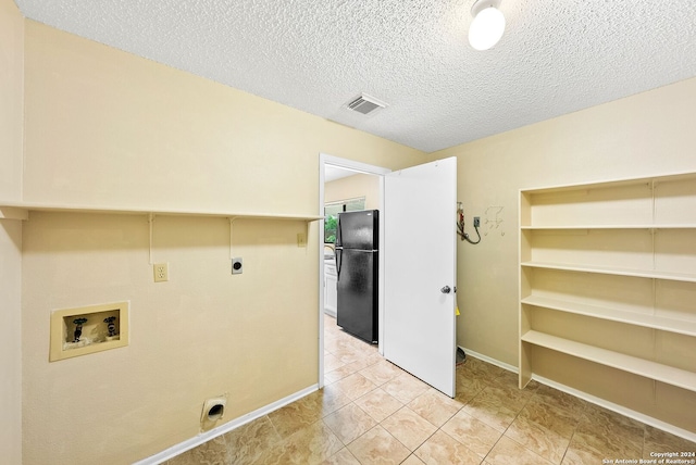 clothes washing area featuring a textured ceiling, hookup for a washing machine, light tile flooring, and electric dryer hookup