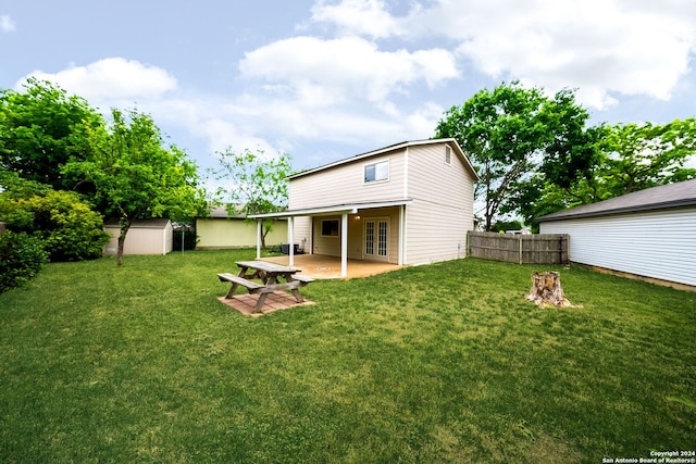 rear view of property featuring a patio, a storage shed, and a yard