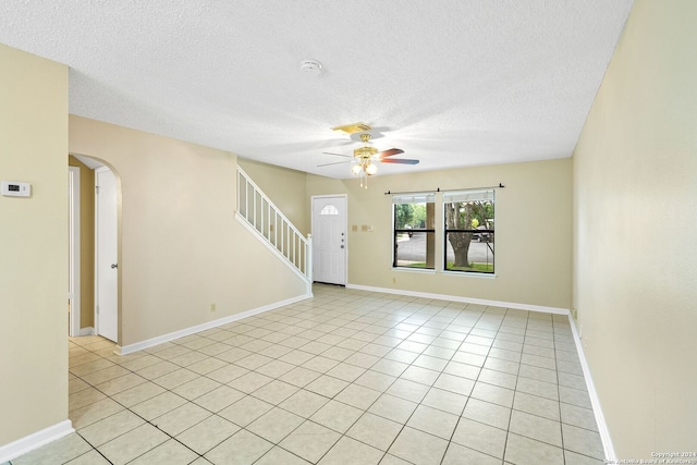 spare room featuring a textured ceiling, ceiling fan, and light tile flooring