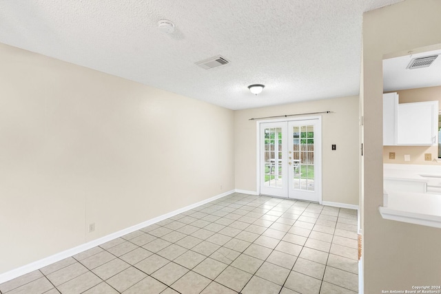 tiled empty room featuring a textured ceiling and french doors