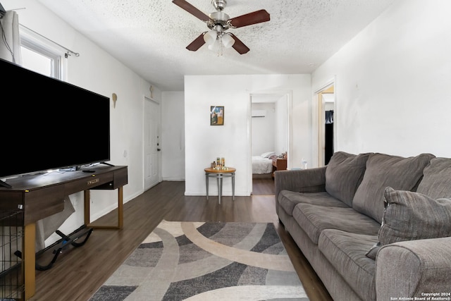 living room featuring dark hardwood / wood-style floors, ceiling fan, and a textured ceiling