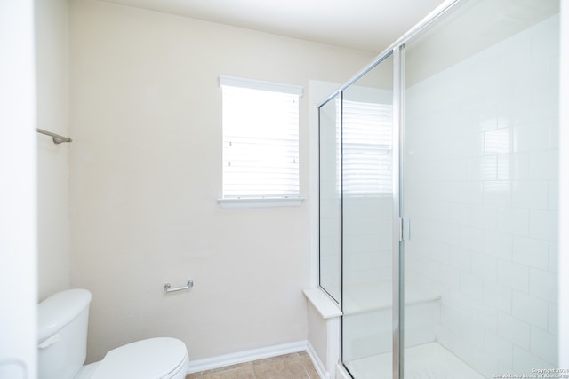 bathroom with tile flooring, toilet, and a shower with shower door