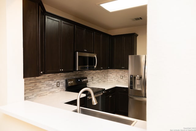 kitchen featuring dark brown cabinets, appliances with stainless steel finishes, backsplash, and sink