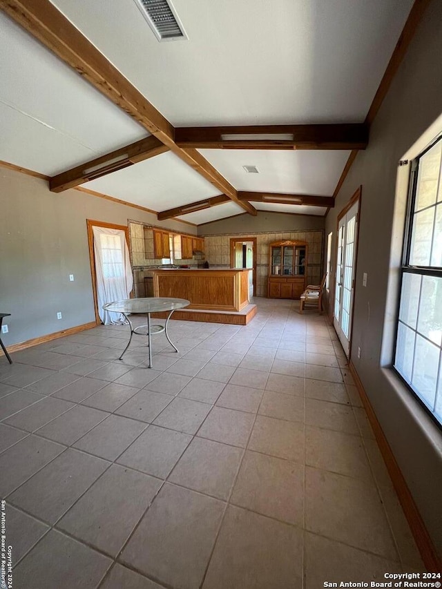 unfurnished living room featuring vaulted ceiling with beams and tile flooring