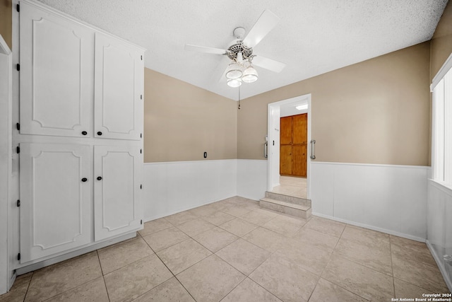 tiled empty room with ceiling fan and a textured ceiling