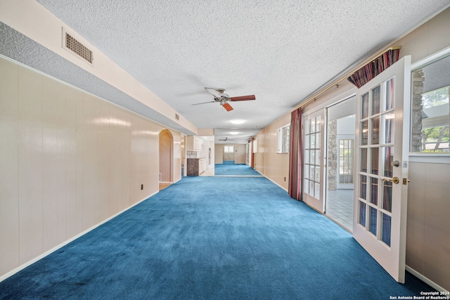 spare room with ceiling fan, carpet flooring, french doors, and a textured ceiling