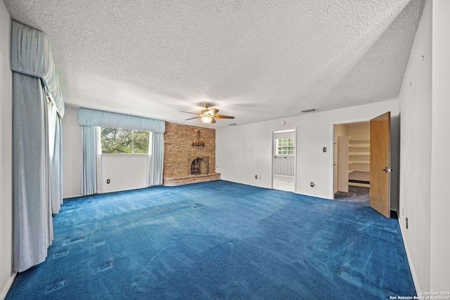 unfurnished living room featuring a large fireplace, a textured ceiling, carpet, and ceiling fan