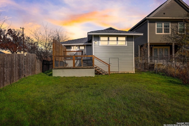 back house at dusk with a deck and a yard