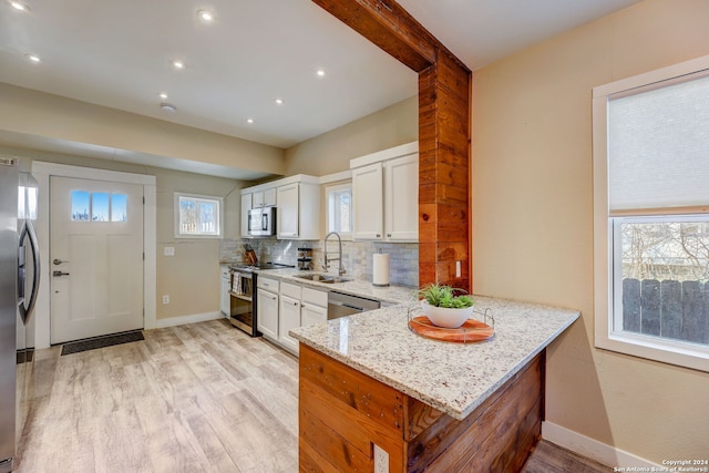 kitchen with white cabinets, sink, light hardwood / wood-style floors, and light stone countertops