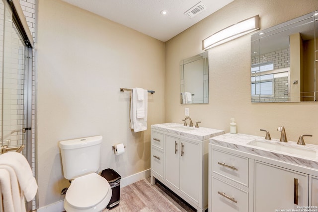 bathroom featuring a textured ceiling, toilet, hardwood / wood-style flooring, and dual vanity