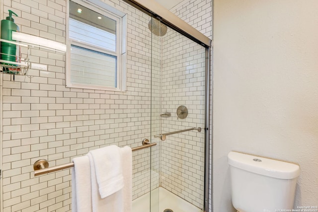 bathroom featuring a shower with door and toilet