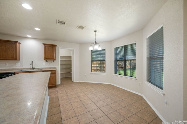 kitchen featuring decorative light fixtures, a textured ceiling, sink, an inviting chandelier, and light tile floors