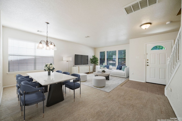 carpeted dining space with a textured ceiling and a notable chandelier