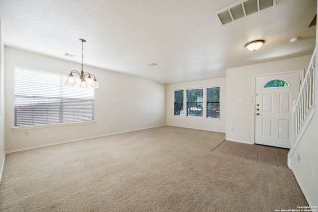 carpeted foyer featuring a textured ceiling and an inviting chandelier