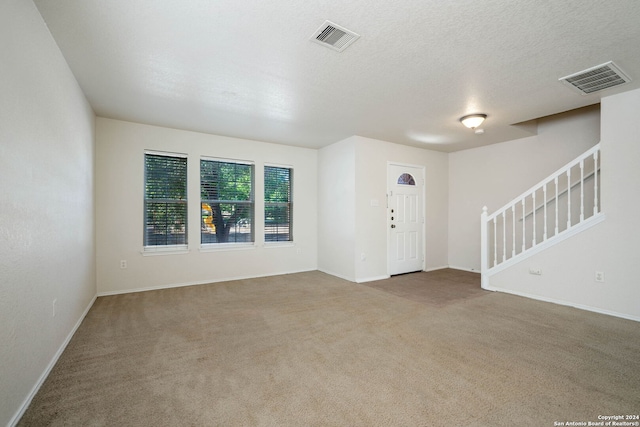 unfurnished living room featuring a textured ceiling and dark colored carpet