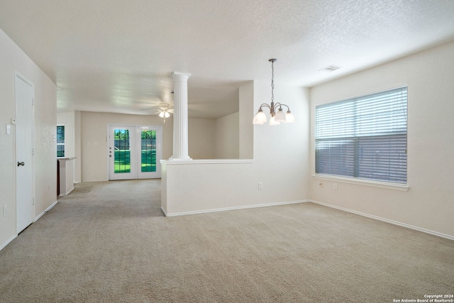 unfurnished room with ceiling fan with notable chandelier, light colored carpet, decorative columns, and a textured ceiling